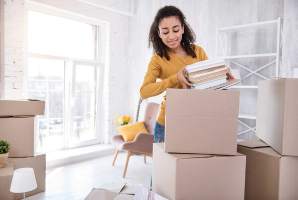 girl-picking-up-books-from-a-box-in-a-dormitory