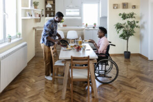 Woman in a wheelchair enjoying a meal with her husband at home - designing inclusive multi-family architecture.