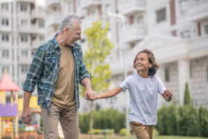 Senior man with his grandson in a playground - amenities of an inclusive multi-family architecture.