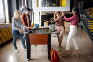 College students playing foosball in their dormitory hall - modern student housing design.