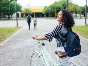 College student riding her bike outside of her apartment - student housing architecture innovations.