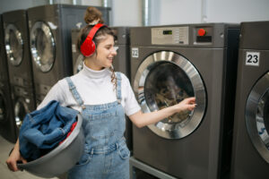 Young woman doing her laundry in her student housing - including laundry rooms in your student housing architecture.