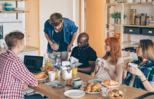 Student housing architecture design - Group of students eating breakfast in a shared kitchen.